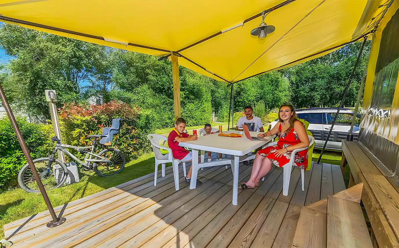 Famille attablée sous la terrasse couverte d’un hébergement insolite près du Puy du Fou