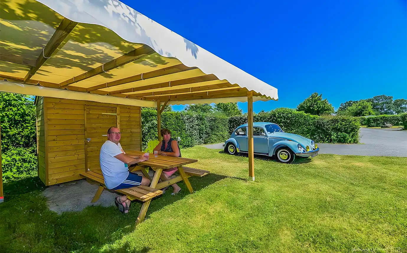Emplacement Privilège Garden avec espace couvert, table en bois et voiture garée sur la parcelle, en Vendée