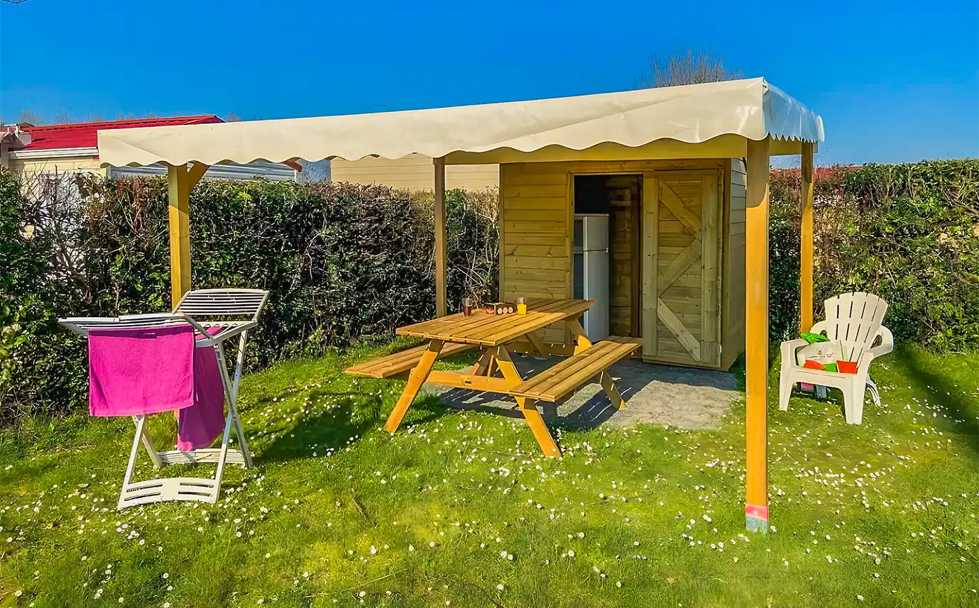 Parcelle Privilège Garden avec abri en bois, table et chaise longue, au camping en Vendée